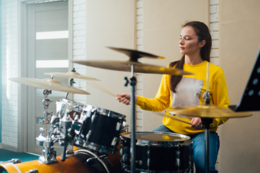 Woman practicing at a drum set.