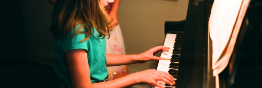 Children reading music on a piano