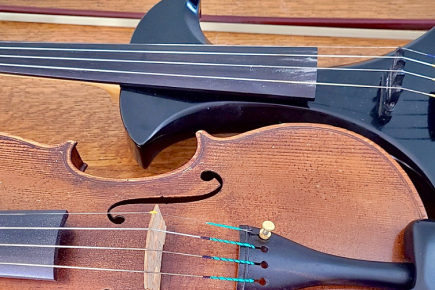 Electric violin and acoustic violin side-by-side on a table.