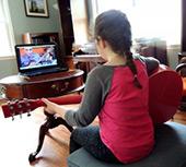 Photo of girl on guitar taking online lessons - credit to Naturally Educational