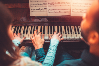 Child and adult playing piano. 