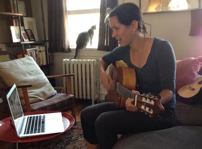 Leah with guitar on computer with cat
