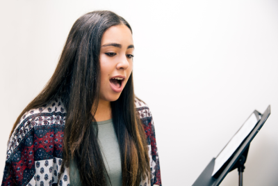 Young woman singing with music stand.