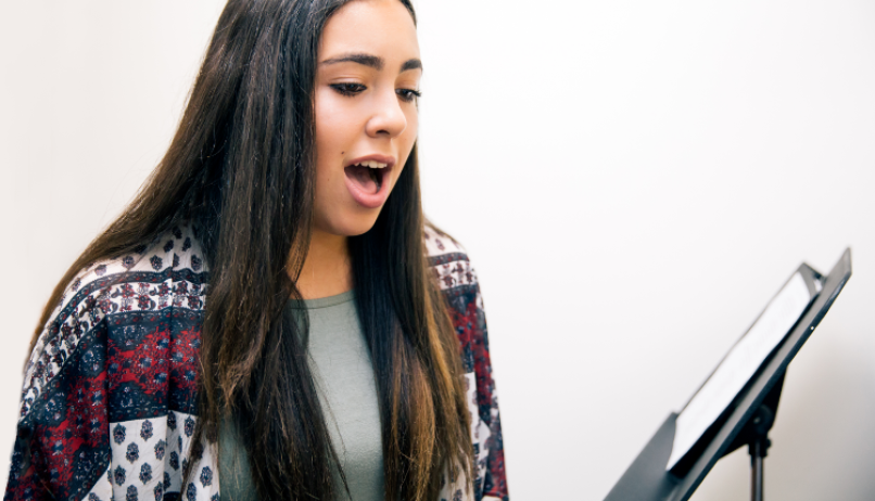 Young woman singing with music stand.