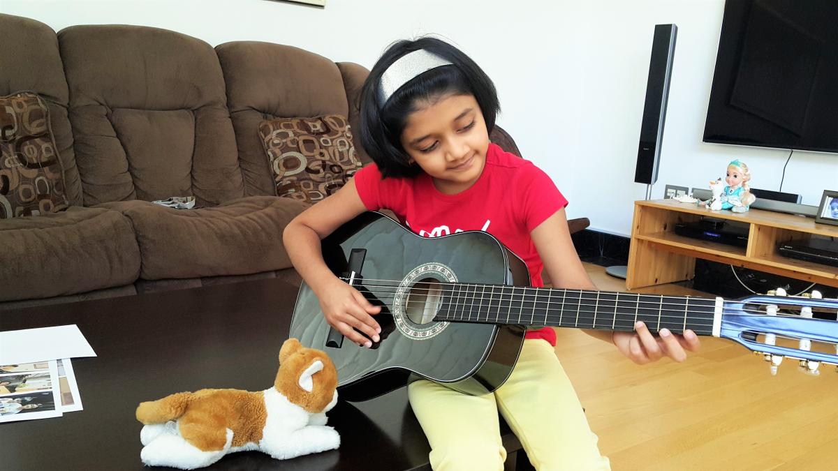 cute little girl concentrating on guitar